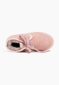 Stivale alla caviglia in suede rosa con fodera in pelliccia sintetica, punta rotonda e design con lacci piatti. Presenta cuciture a tono e un interno morbido e texturizzato.