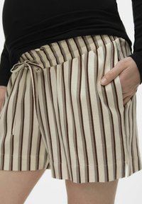 Stribede shorts lavet af letvægtsstof, med beige og brune lodrette striber, en elastisk talje med snøre og sidelommer.