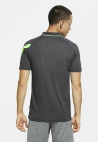 Schwarzes kurzärmliges Poloshirt mit schlanker Passform, das einen grünen Akzent an der Schulter und einen gerippten Kragen aufweist. Glattes, leichtes Material.
