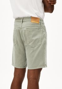 Lichtgroene katoenen shorts met een gestructureerde afwerking, voorzien van achterzakken en een bruine leren merketiket.