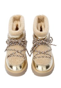 Beige fluffy støvler med metalliske guld accenter, der har tekstureret pelsforing, vævede snørrebånd med sorte og brune detaljer og gummisåler.