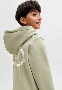 Felpa verde chiaro in morbido tessuto, con un grande logo bianco sul retro. Progettata con cappuccio regolabile e polsini a coste.
