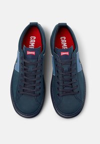 Navy blue leather sneakers featuring contrasting light blue panels, round toe, lace-up design, and red insoles with white "CAMPER" logo.