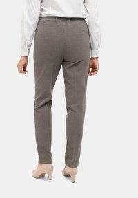 Grijze op maat gemaakte broek met een slim fit, voorzien van een gladde textuur, achterzakken en een elastiche tailleband. Gemaakt in combinatie met beige hoge hakken.