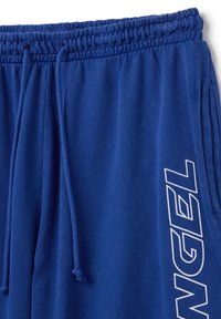Blue sweatpants made of soft fabric, featuring an elastic waistband with drawstring, side pockets, and "ANGEL" printed in white on the leg.
