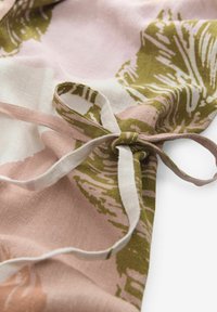 Blommönstrad tyg i rosa och gröna nyanser, med en texturerad linne-material och en vit snörning för fastsättning.