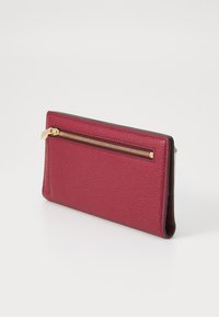 Raspberry leather wallet with a gold zipper, textured surface, and a slim profile. Features a single zipper compartment on the front.