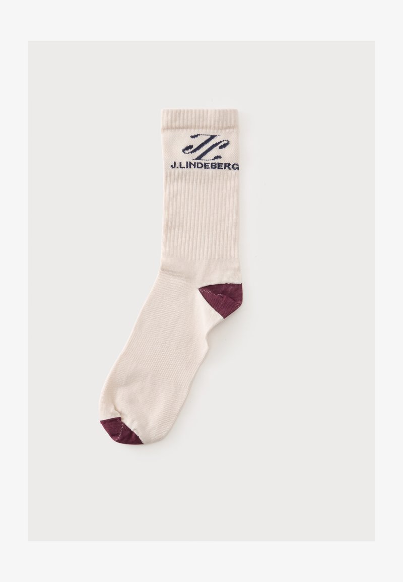 Chaussette beige mi-haute avec partie supérieure côtelée, accents violet foncé sur la pointe et le talon, et logo J. Lindeberg noir près du bord.