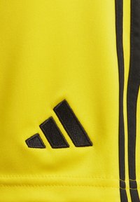 Geel atletiekshirt met zwart Adidas-logo en drie strepen, gemaakt van textuurstof. Accentueert met zwarte strepen langs de zijkanten.