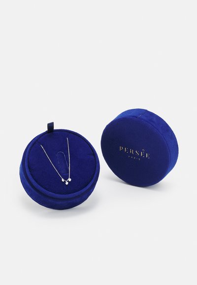 Apvalus, aksominis papuošalų dėžutė tamsiai mėlyna su auksine užrašu. Joje yra sidabrinė kaklo grandinėlė su trimis mažais ašarėlės formos pakabukais.