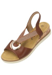 Sandalo in pelle marrone con una larga fascia e dettaglio con anello metallico. Tacco in sughero testurizzato e bande in tessuto elastico per supporto. Suola leggera.