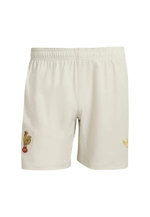 Hvide sportsshorts med elastisk linning, der har en gylden hane-patch på venstre ben og et lille gult Adidas-logo på højre ben.