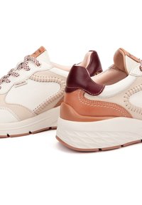 Baskets en cuir blanc et beige avec un accent bordeaux, des coutures texturées, des lacets ronds et une semelle épaisse et profilée.