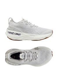 Weiße Sportschuhe aus Mesh und Gummi; verfügen über eine gepolsterte Sohle, eine abgerundete Spitze und Textdetails an der Seite. Strukturierte Oberflächengestaltung.
