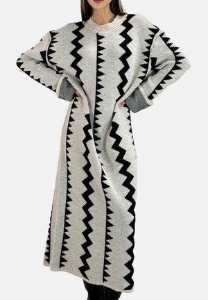 Langes Strickkleid mit einem schwarz-weißen Zickzackmuster, einem gerippten Ausschnitt und weiten Ärmeln. Weiche Textur mit lockerem Sitz.