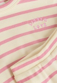 Camicetta a maniche lunghe a righe crema e rosa, texture a coste, ricamo con testo "Wild Love", scollatura rotonda, dettaglio polsino piegato.