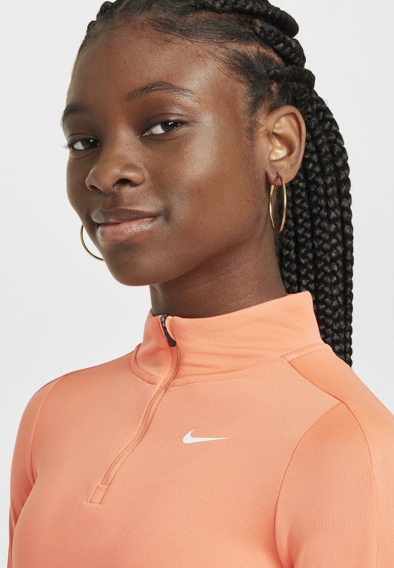 Langärmliges, Reißverschluss-Sportoberteil in lebhaftem Korallenrot mit glatter Textur und einem weißen Nike-Logo auf der Brust. Einfaches, tailliertes Design.