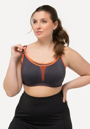 Grijze sportbeha met oranje accenten, met een netontwerp in het midden, verstelbare bandjes en een gladde textuur. Zwarte high-waisted leggings.
