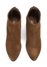 Bottines en suède marron avec un bout pointu et une fermeture éclair à l'arrière. Texture lisse avec un design minimaliste, semelle plate.