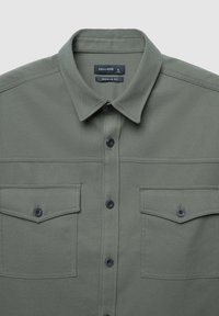 Camicetta verde oliva con colletto, due tasche sul petto e bottoni blu navy; realizzata in tessuto testurizzato con un design a vestibilità normale.