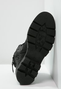 Czarny but na zamek z teksturowaną cholewką i wytrzymałą gumową podeszwą, z wzorem sześciokątnych i kwadratowych elementów bieżnika.