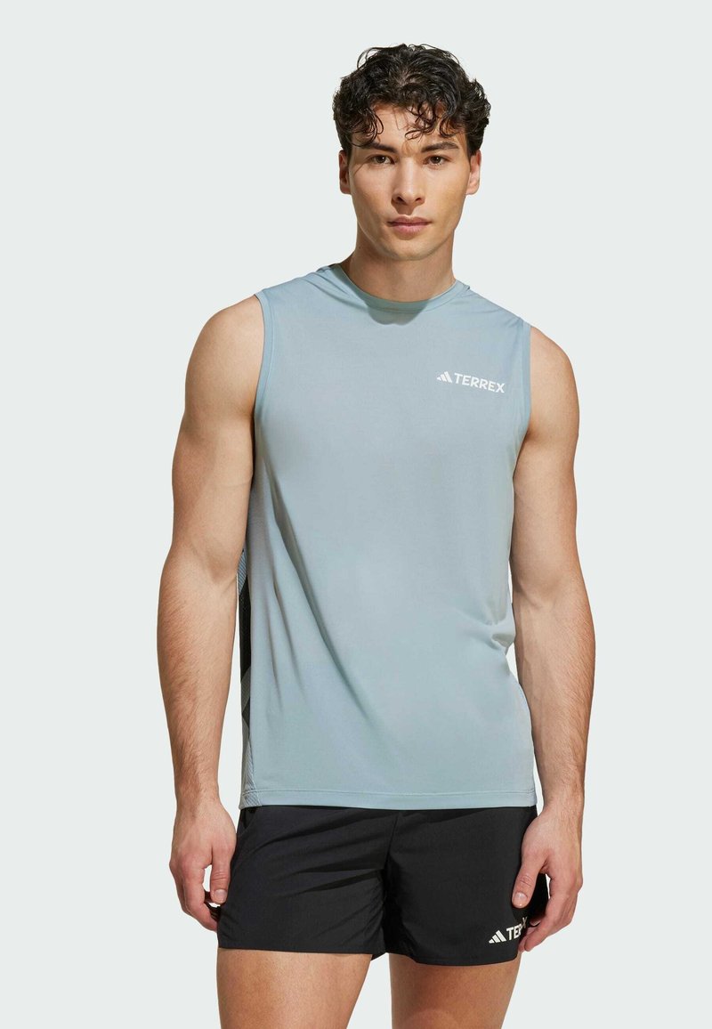 Lichtblauw mouwloos sporttop gemaakt van vochtafvoerend materiaal. Heeft een ronde halslijn en een wit Terrex-logo op de borst.