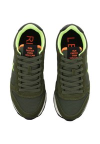 Pár bežeckých topánok olivovej zelenej farby s jasne limetkovým vnútorným podšitím, čiernymi vložkami a červeným textom "BEŽ RÝCHLEJŠIE, AKO MÔŽEŠ" na jazyku.