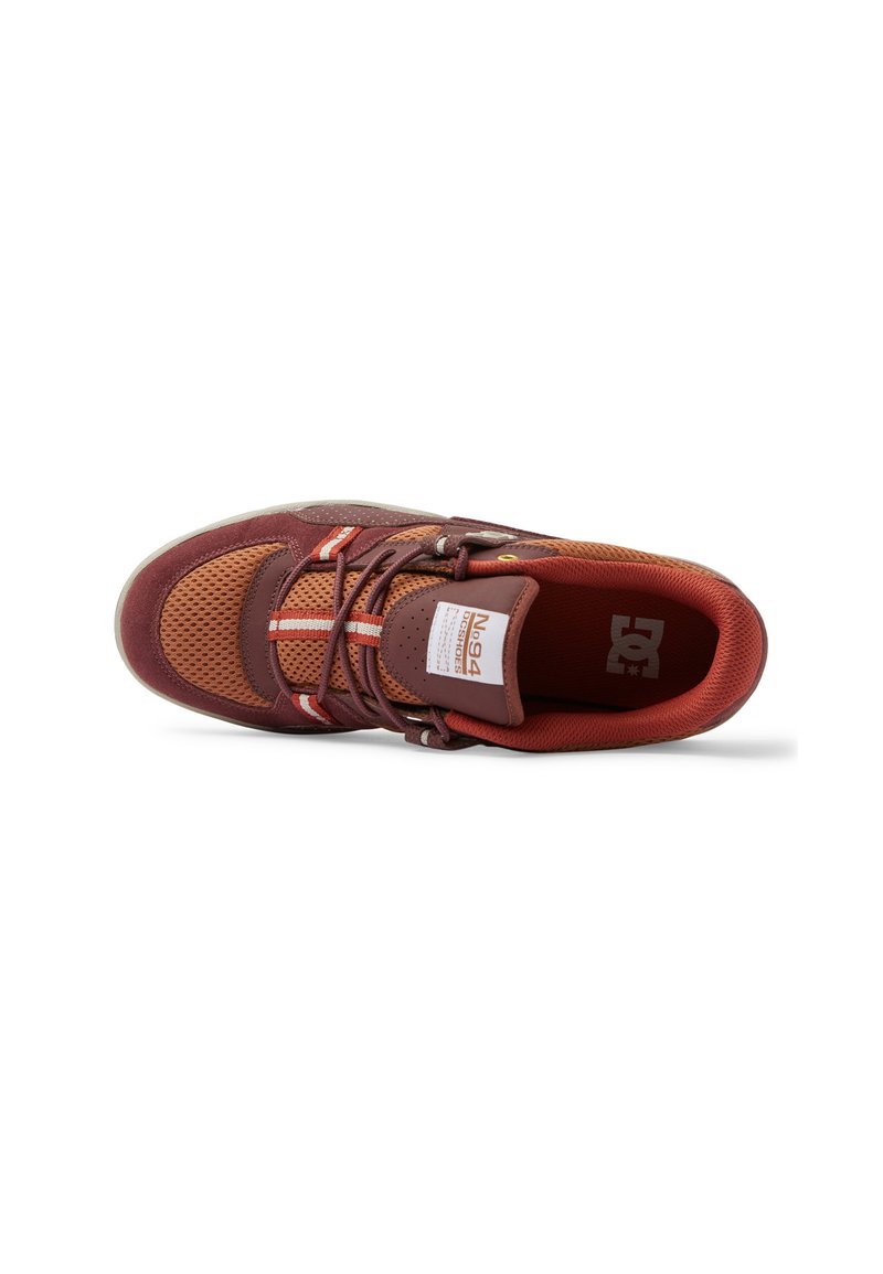 Chaussure de sport marron et orange avec tige en mesh, col rembourré et lacets contrastants. Présente un logo blanc sur la languette et une semelle texturée.
