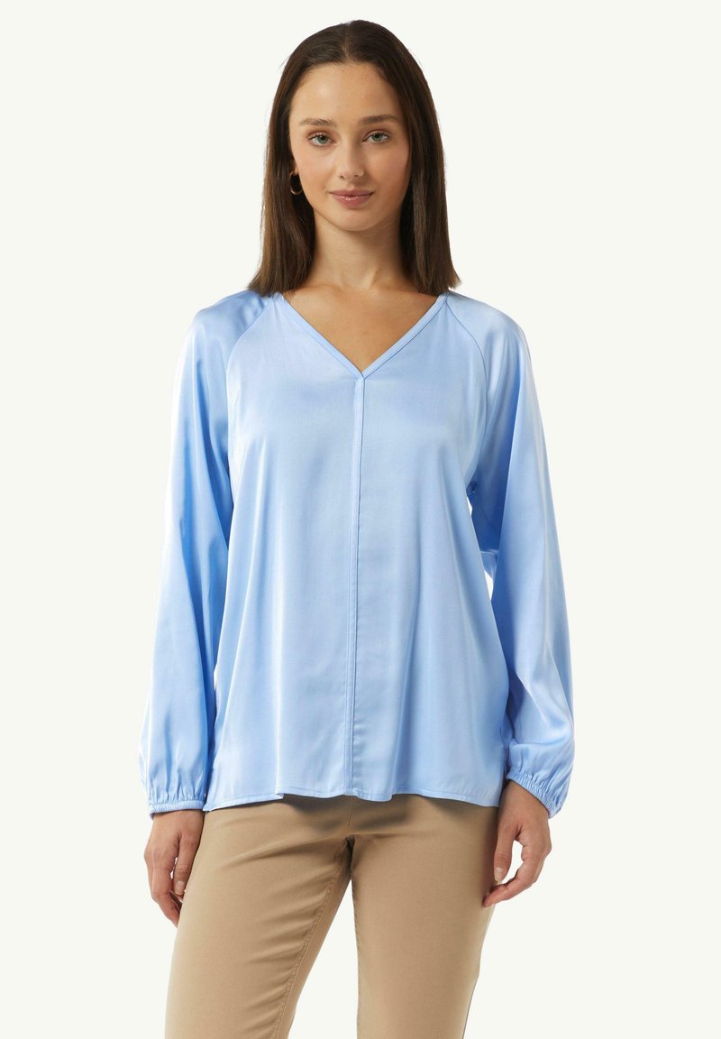 Hellbluse aus Satin mit V-Ausschnitt und langen Raglanärmeln, featuring elastischen Bündchen und geradem Saum, glatte Textur.