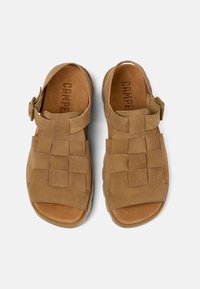 Brown suede sandals with a woven upper design, open toe, and adjustable strap for fit. Textured footbed with CAMPEON branding.