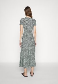 Black and white patterned maxi dress with short sleeves and a fitted bodice, featuring a flared skirt and a soft, stretchable fabric.