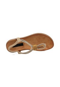 Sandalia de dedo beige con una correa trenzada y una plantilla texturizada en tono marrón. Presenta un acento decorativo de hardware dorado y un material superior suave.