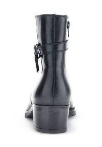 Bottine en cuir noir avec un petit talon, dotée d'une fermeture éclair sur le côté, d'une sangle avec une boucle, et d'une texture lisse. La vue arrière met en avant un design élancé.