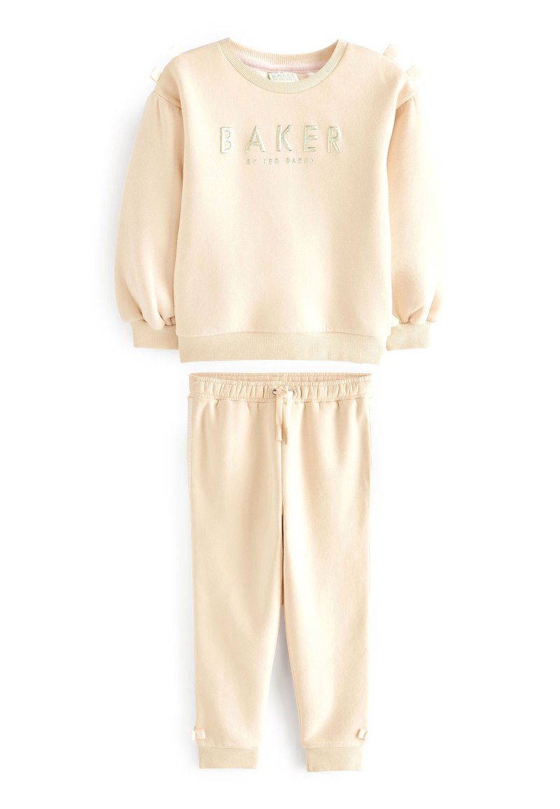 Ensemble en sweat-shirt beige et joggers en tissu doux. Le sweat-shirt présente des manches froncées et "BAKER" brodé à l'avant. Taille élastique sur les joggers.