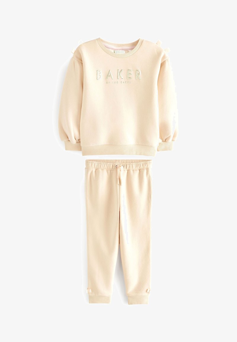 Béžová mikina a súprava teplákov vyrobená z mäkkého materiálu. Mikina má na rukávoch nariasenie a na prednej strane je vyšité slovo "BAKER". Tepláky majú elastický pás.