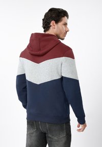 Φούτερ με κουκούλα και σχέδιο βέλος σε μπορντό, γκρι και ναυτικό μπλε. Κατασκευασμένο από απαλό ύφασμα, διαθέτει τσέπη τύπου καγκουρό και ριμπ μανσέτες.