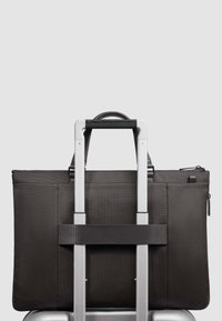 Schwarze Laptop-Tasche aus Stoff mit strukturiertem Finish, ausgestattet mit einem oberen Griff und einem Riemen, der sie an einem silbernen Trolleygriff sichert.