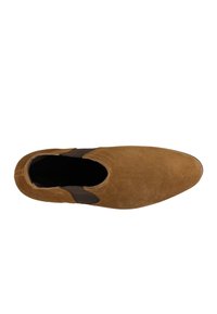 Braune Wildleder-Slipper mit einer abgerundeten Zehenpartie, ausgestattet mit elastischen Seiteneinsätzen für ein einfaches Anziehen und einer glatten, strukturierten Oberfläche.