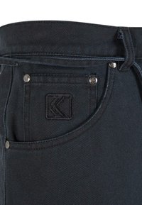 Black denim pants featuring a visible inner waistband, embroidered logo patch, and metallic rivets on pocket edges.