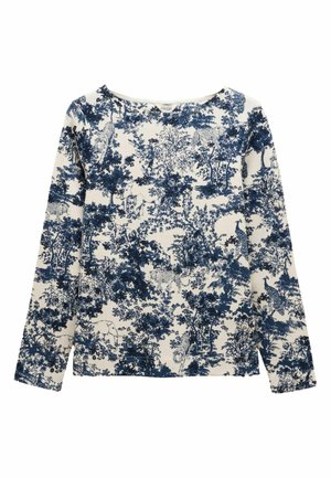 Long-sleeve top in cream with a blue wildlife pattern featuring trees, animals, and foliage. Soft fabric, wide neckline, and relaxed fit.