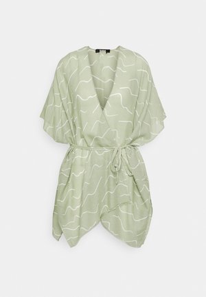 Vestito incrociato verde chiaro con strisce bianche ondulate, maniche corte, cintura in vita e orlo asimmetrico su sfondo neutro.