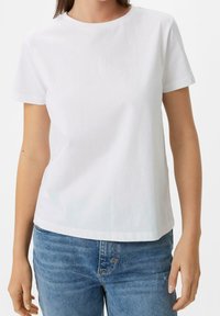 Camiseta de algodón blanca con cuello redondo y mangas cortas, que presenta un sutil logotipo bordado en el pecho y un corte recto.