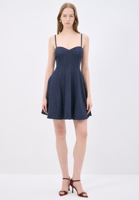 Laivansinis mekko ohuilla hihnoilla, istuvalla bodicella, levenevällä hameella ja pystysuoralla ribbitekstuuri. Huomattava sydänleikkaus ja sileä kangas.