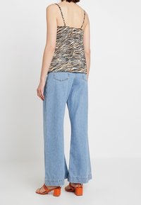 Camisole top s tygrovaným potiskem, volné světle modré džíny, sandály na blokovém podpatku v oranžové barvě, se nastavitelnými ramínky a širokým střihem.