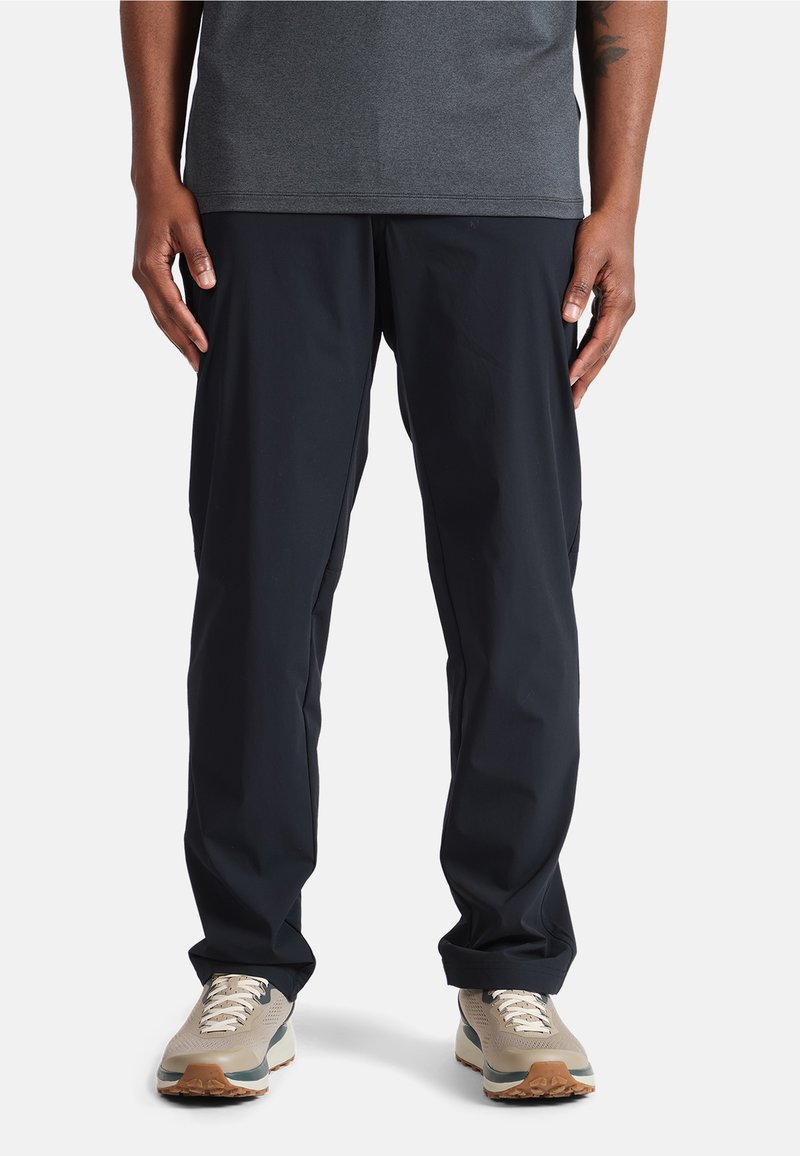 Pantalons légers bleu marine avec une coupe ample, dotés d'une texture douce et de poches latérales discrètes, associés à des chaussures de course dans des tons neutres.