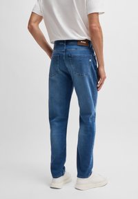 Blå denimjeans med rak passform, bakficka med patch och märkets lädertag. Kommer i kombination med vita sneakers och en enkel T-shirt.