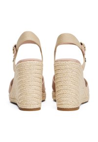 Beige wedge sandals with braided rope heels, ankle straps, and gold buckle closures viewed from the back.