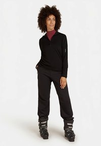 Conjunto negro con cremallera y pantalones a juego, hechos de material elástico. Cuenta con cuello alto y botas de esquí, proporcionando un conjunto elegante para deportes de invierno.