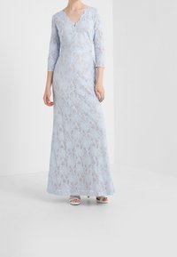 Ljusblå spetsklänning med en vågig V-ringning, trekvartslånga ärmar och en figurnära bodice som övergår i en flödande kjol.