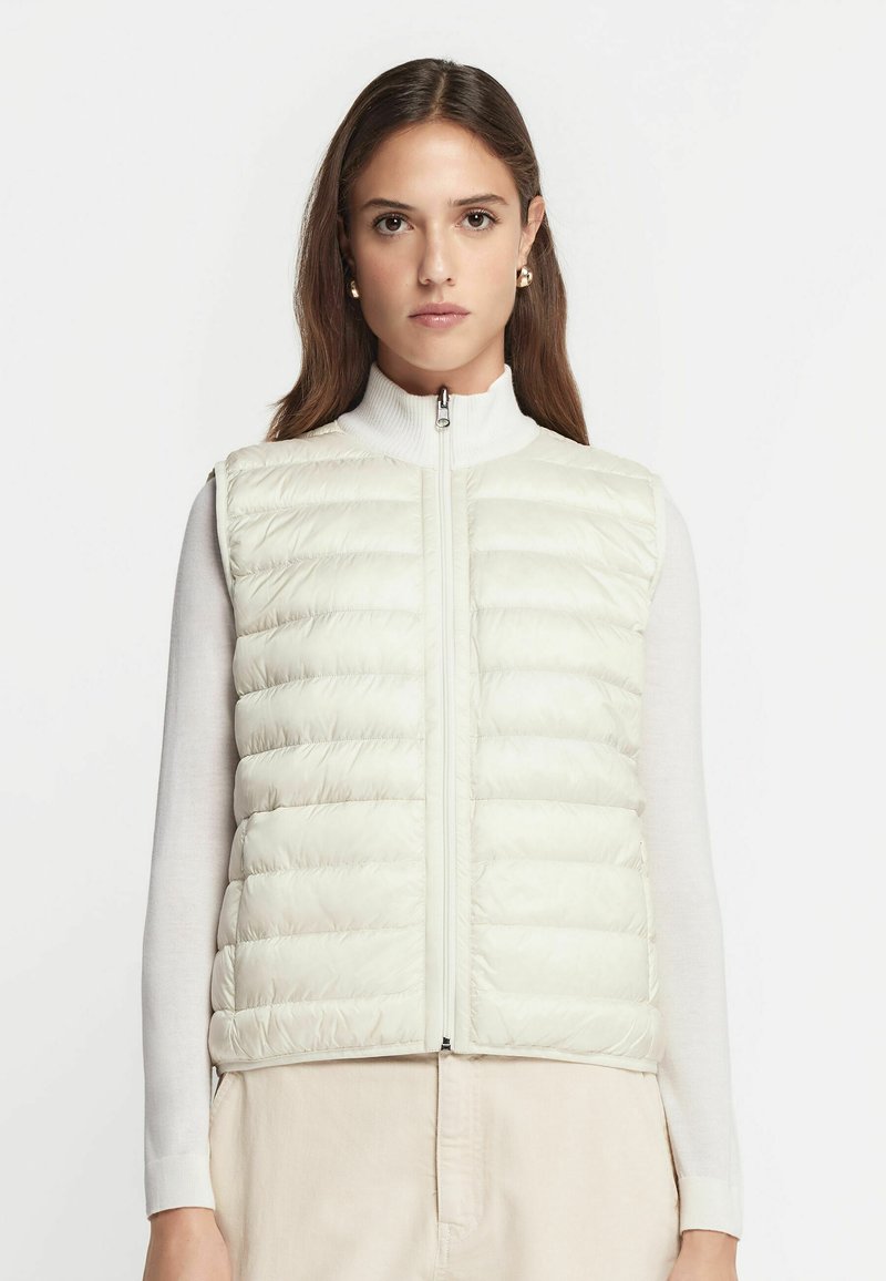 Lichtgewicht, crèmekleurige puffer vest met een ritssluiting aan de voorkant, horizontaal gestikte delen, hoge kraag en een gladde textuur.